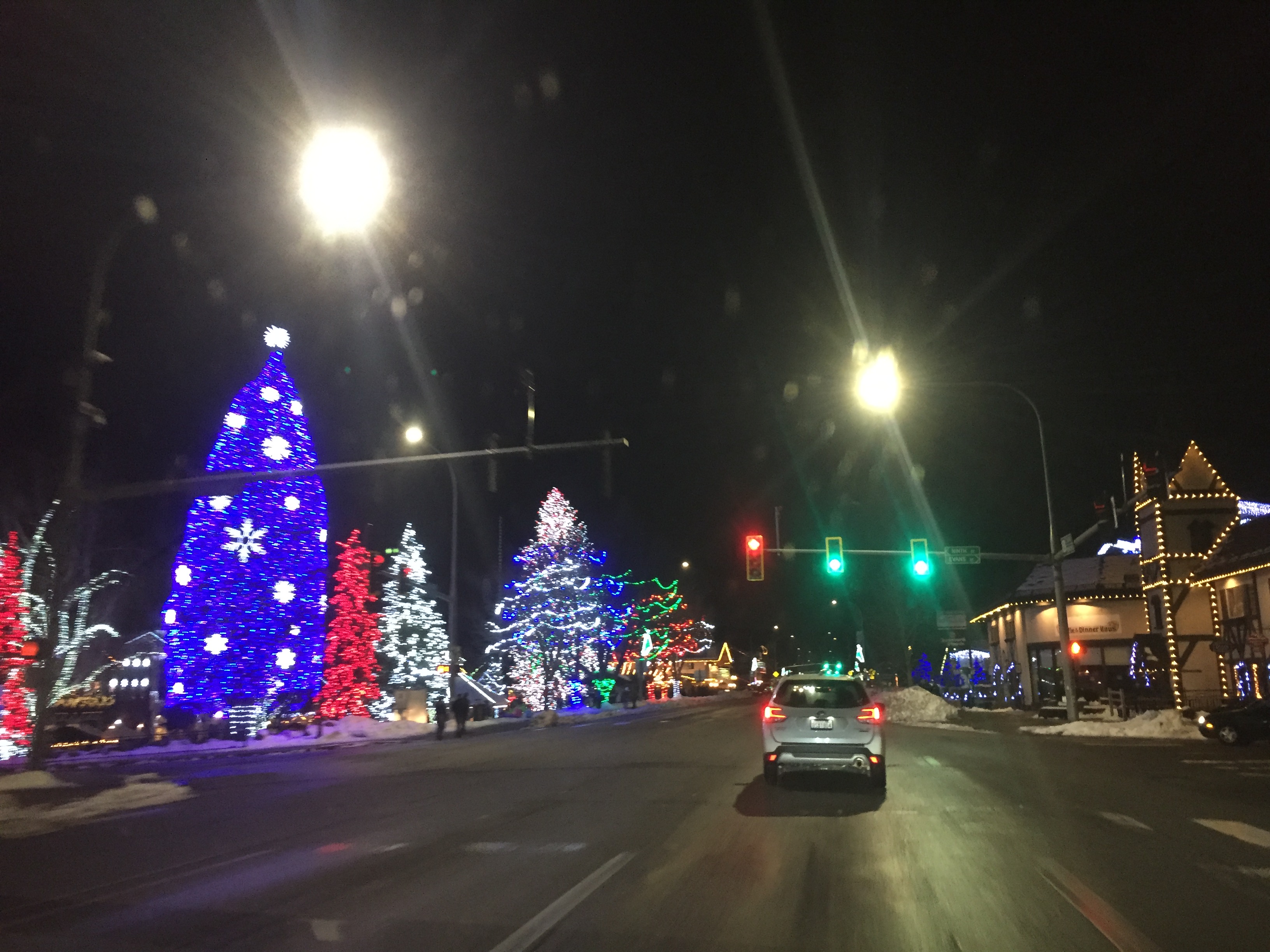Christmas lights and decorations at night with car driving down road