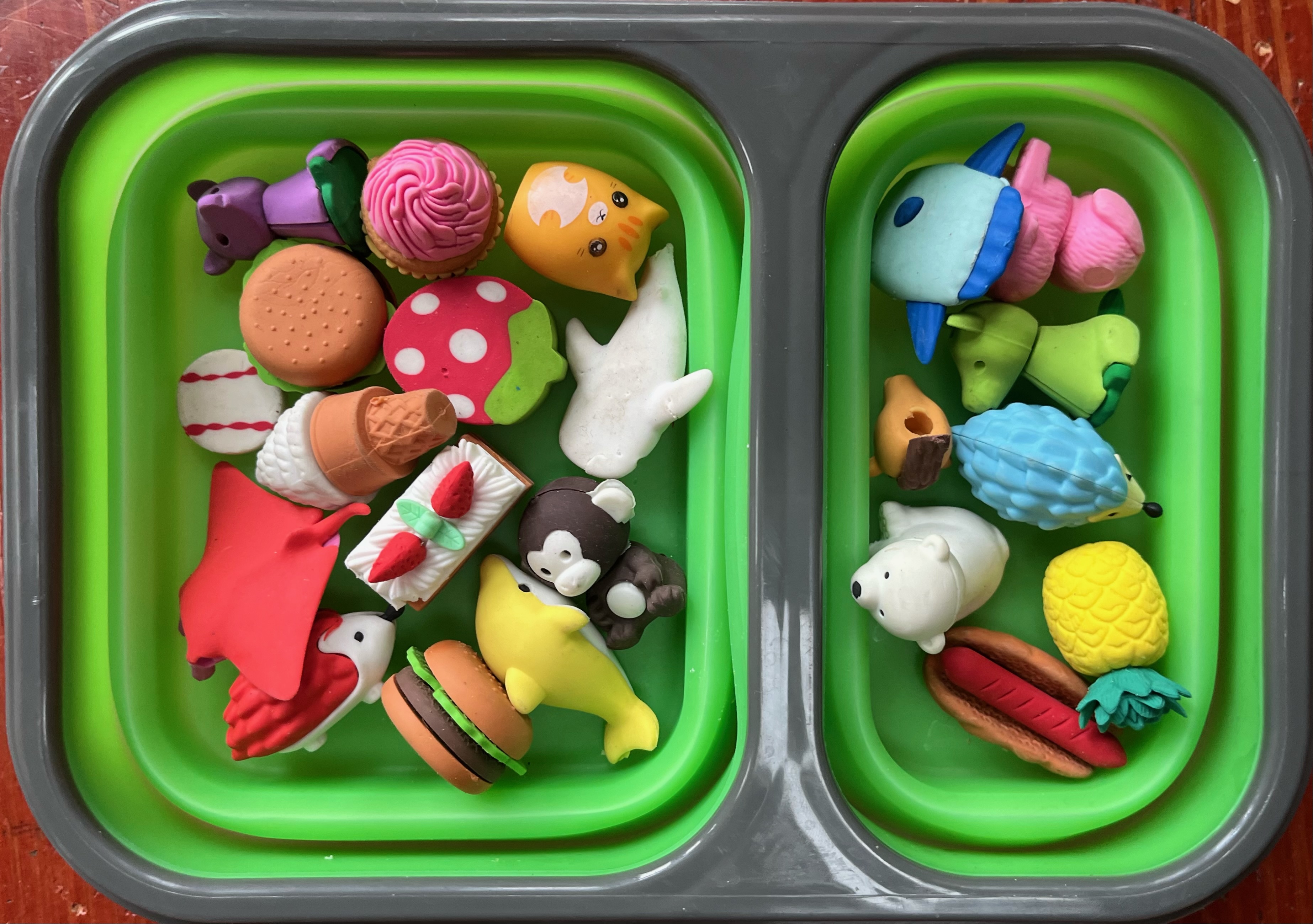 Green collapsible lunch box filled with brightly colored animal erasers in polar bear, pink poodle,