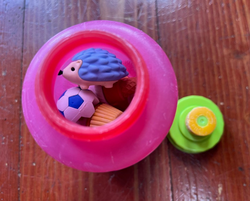 Hot pink translucent kids' water bottle with lime green lid open beside it used to store animal erasers inside