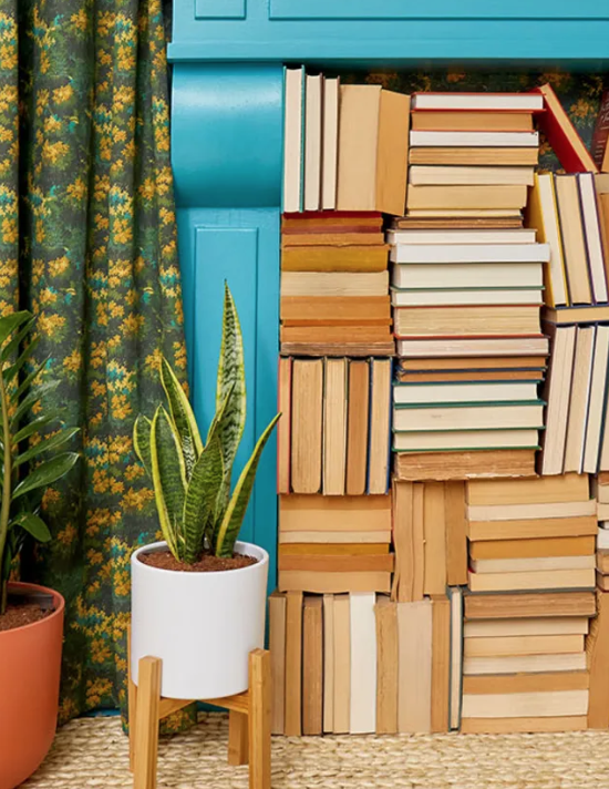 Books stacked in faux fireplace with spines facing out from Apartment Therapy's Small Cool 2023 Contest