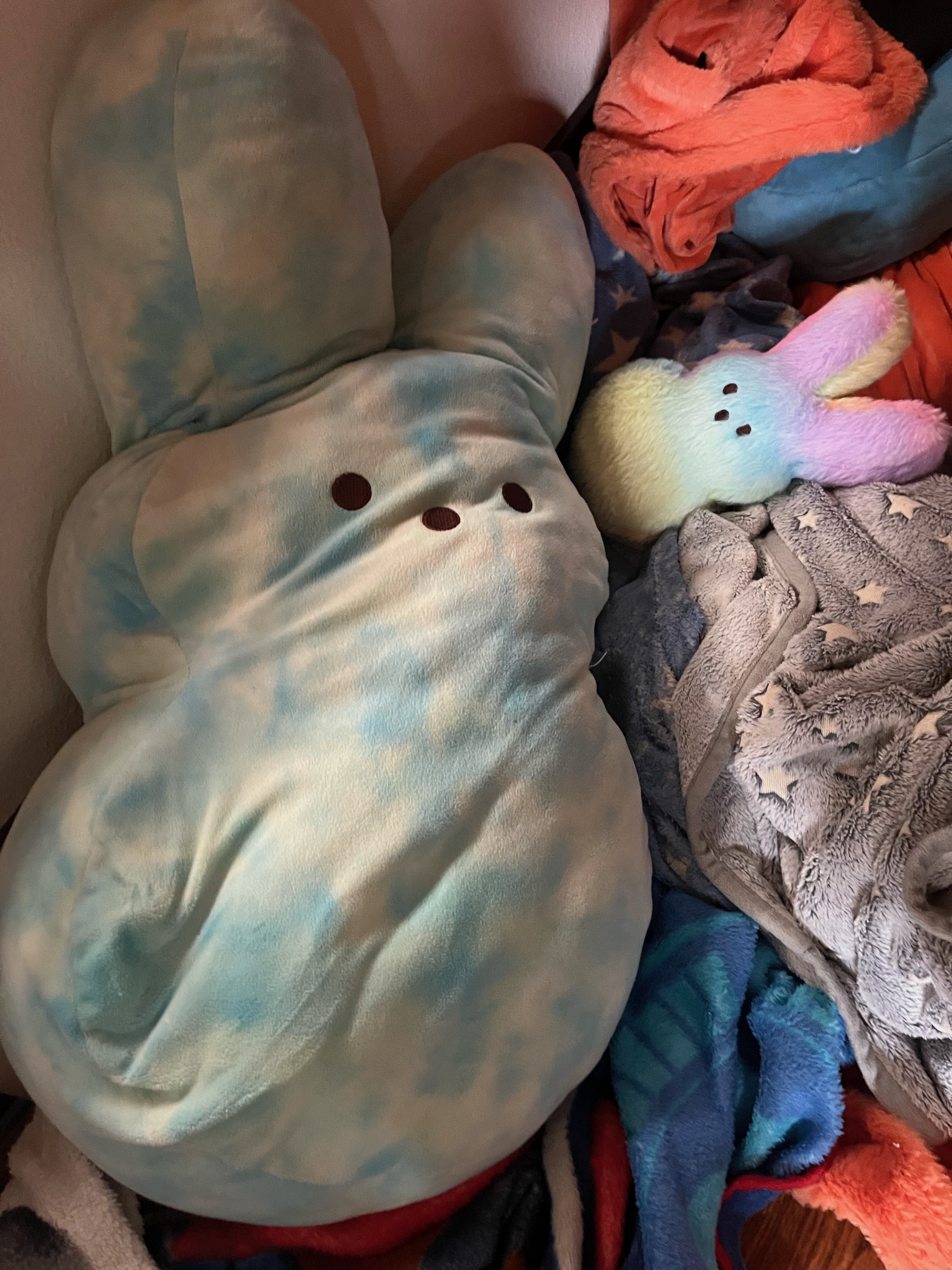 Jumbo Peeps stuffed animal in blue and whit pattern with small rainbow peep nestled in blankets and covers