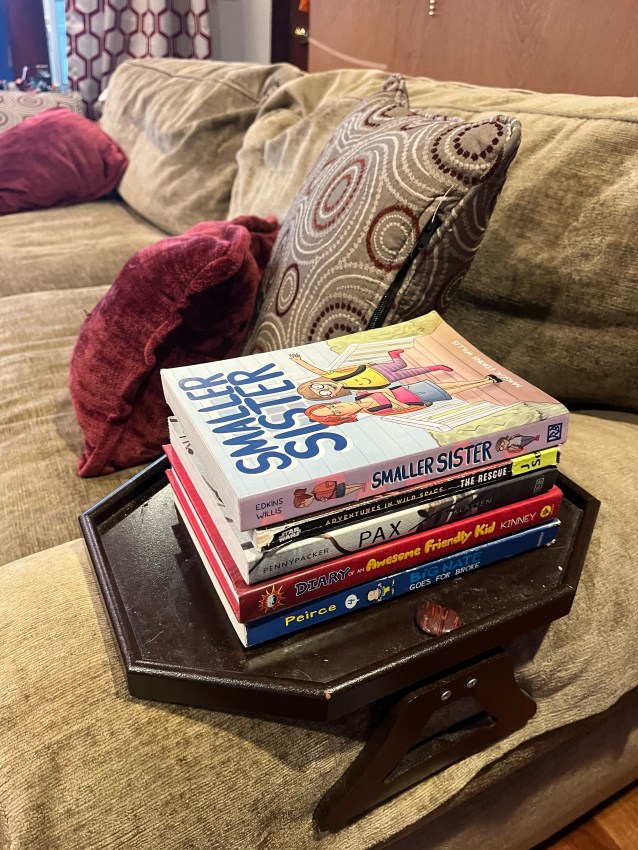 Books stacked on armrest side table on sofa